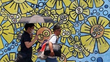 Pedestrians shield themselves from the scorching heat while walking along EDSA in Quezon City on April 18, 2024.