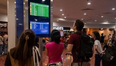 Passengers look at a screen showing flight information at terminal 3 of Ninoy Aquino International Airport in Pasay, Metro Manila on January 1, 2023. Thousands of travellers were stranded at Philippine airports on January 1 after a &quot;loss of communication&quot; at the country's busiest hub in Manila forced hundreds of flights to be cancelled, delayed or diverted.