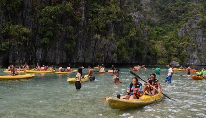 This photo taken on December 12, 2023 shows tourists paddling their kayaks while others take photos inside the Big Lagoon in El Nido town, Palawan province. 