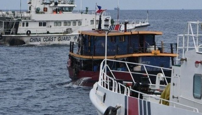 Chinese coast guard ships (L and R) corral a Philippine civilian boat chartered by the Philippine navy to deliver supplies to Philippine navy ship BRP Sierra Madre in the disputed South China Sea, on August 22, 2023