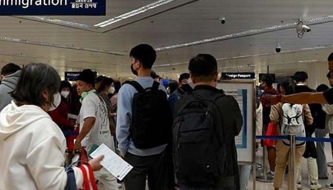 An airport security guides visitors from China as they arrive at Ninoy Aquino International Airport in Paranaque, Metro Manila on January 24, 2023.