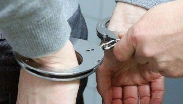 This photo shows a picture of a hand in handcuffs. 