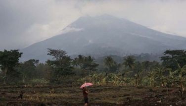 A resident holding an umbrella stands in a lot near their house at the foot of Mount Kanlaon volcano in a village in La Castellana, Negros Occidental province, central Philippines on June 4, 2024, a day after the volcano erupted.