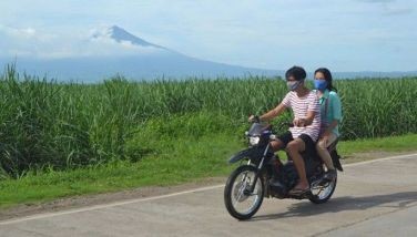 This photo taken on June 24, 2020 shows motorcyclists riding along a road with Kanlaon volcano in the background as seen from the town of Isabela, Negros Occidental, central Philippines.