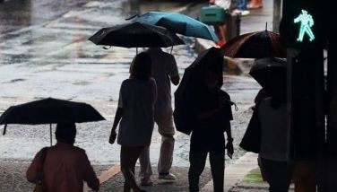 Pedestrians use umbrellas and other items to shield themselves from the sudden downpour in Quezon City on May 25, 2024.