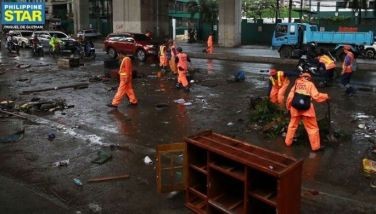 Workers from the Department of Public Works and Highways (DPWH) conduct a clearing operation to remove rubbish and mud along G. Araneta Avenue in Quezon City on July 25, 2024 after the onslaught of #CarinaPH and the southwest monsoon. 