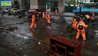 Workers from the Department of Public Works and Highways (DPWH) conduct a clearing operation to remove rubbish and mud along G. Araneta Avenue in Quezon City on July 25, 2024 after the onslaught of #CarinaPH and the southwest monsoon. 