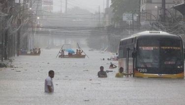 A bus stalls in the middle of E. Rodriguez Avenue while rescue personnel from the QCDRRMO and Barangay Damayan Lagi in Quezon City ferry stranded commuters and residents across the heavy flood due to torrential rains brought by Typhoon Carina and the habagat on July 24, 2024.