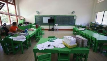 A teacher (L) works inside an empty classroom after in-person classes were suspended due to dangerous levels of heat, at an elementary school in Iloilo City on April 2, 2024.