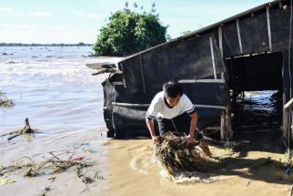 A resident removes grass from his flooded house after a river dike burst at the height of Super Typhoon Man-yi (local name Pepito) at a farming village in Aliaga, Nueva Ecija province on Nov. 19, 2024.