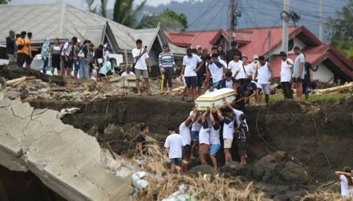 Mourners carry a coffin up a collapsed riverbank and other debris, damaged by floodwaters during heavy rains brought about by Tropical Storm Trami, during a funeral procession in Laurel town, Batangas province on October 30, 2024. Trami rammed into the Philippines on October 24, forcing over half a million people to flee their homes, while at least 42 people remain missing in the storm's aftermath, according to the national disaster agency.