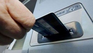 This undated photo shows a person inserting their card into an automated teller machine. 