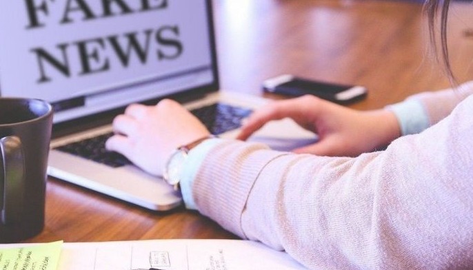 Stock photo shows a woman on a laptop showing &quot;fake news.&quot; 