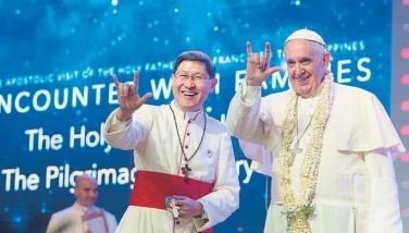 A handout picture taken and released on January 16, 2015 by the Osservatore Romano shows Pope Francis (R) and Archbishop of Manila Luis Antonio Gokim Tagle gesturing during a meeting with families in Manila on January 16, 2015. 