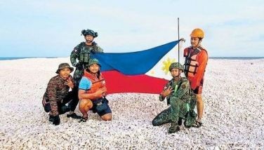 Photo provided by the National Task Force West Philippine Sea shows members of the Navy, Philippine Coast Guard and PNP-Maritime Group holding the Philippine flag as they visited Sandy Cay 2 in the West Philippine Sea on Sunday.