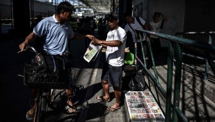 In this May 10, 2016 photo, a Filipino man (L) buys a newspaper on the Philippines presidential frontrunner and Davao City Mayor Rodrigo Duterte the morning after the election in Manila on May 10, 2016. 