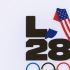 A LA28 (Los Angeles 2028) logo is pictured with French and US national flags during the event celebrating the arrival of the Olympic flag at Los Angeles International Airport (LAX) in Los Angeles, on August 12, 2024. Los Angeles will host the 2028 Summer Olympic Games. The arrival marks the official Olympic Flag’s return to Los Angeles for the first time in 40 years.